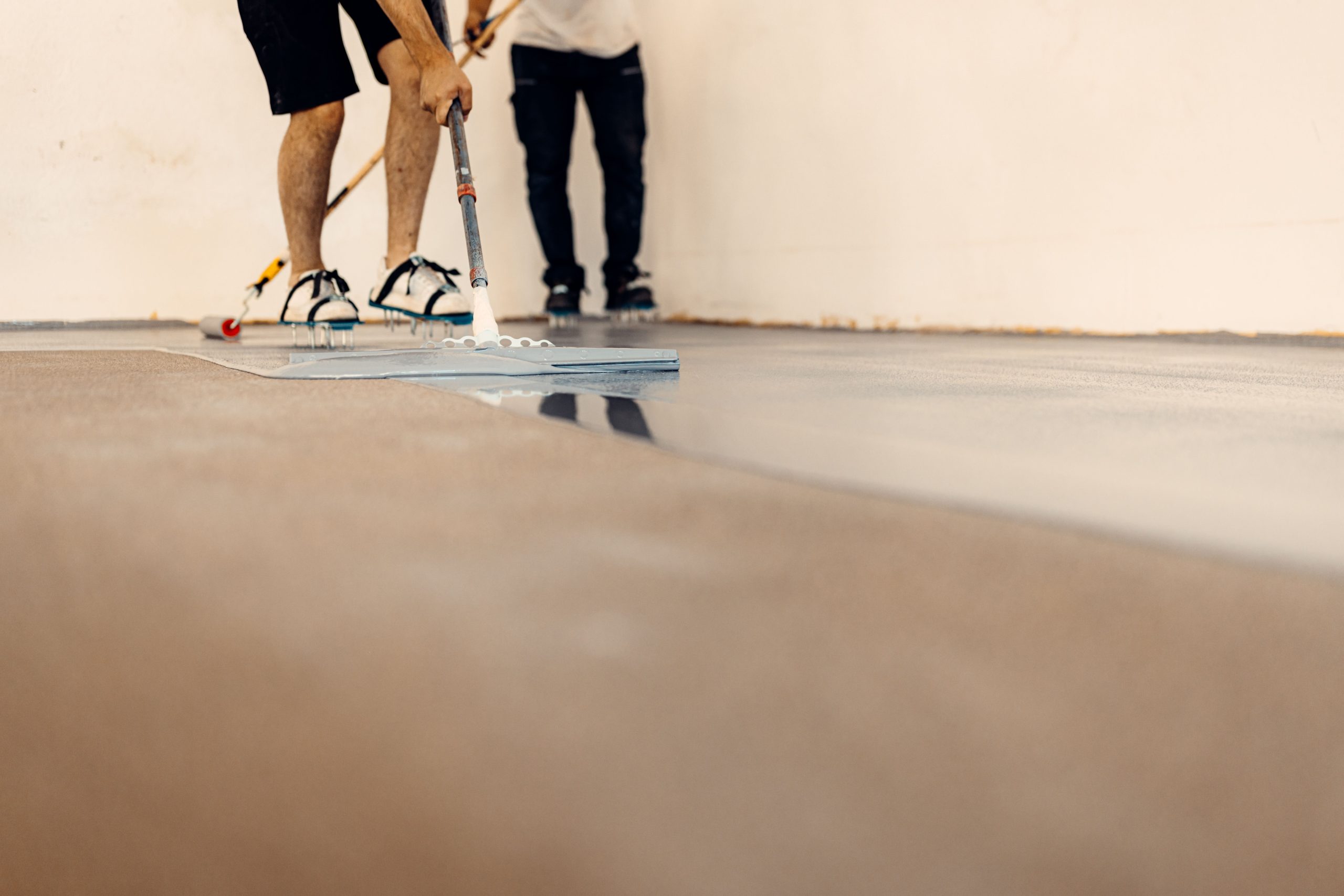 A closeup shot of worker applying floor primer with a special tool